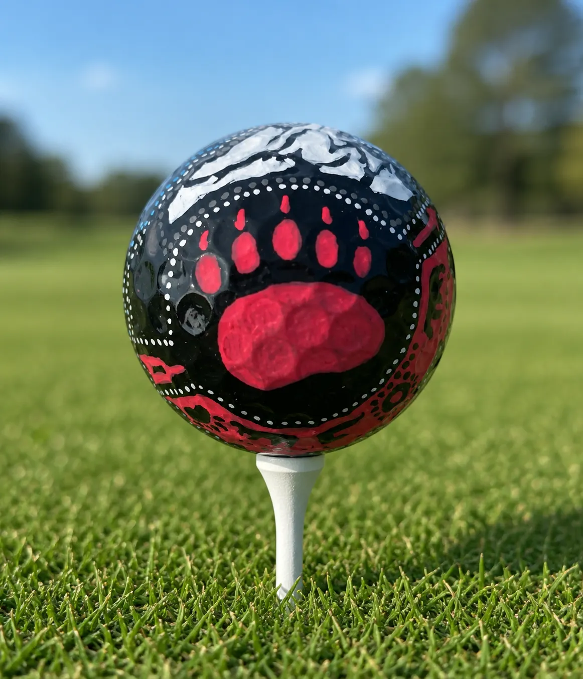 Golf ball painted with a red bear paw