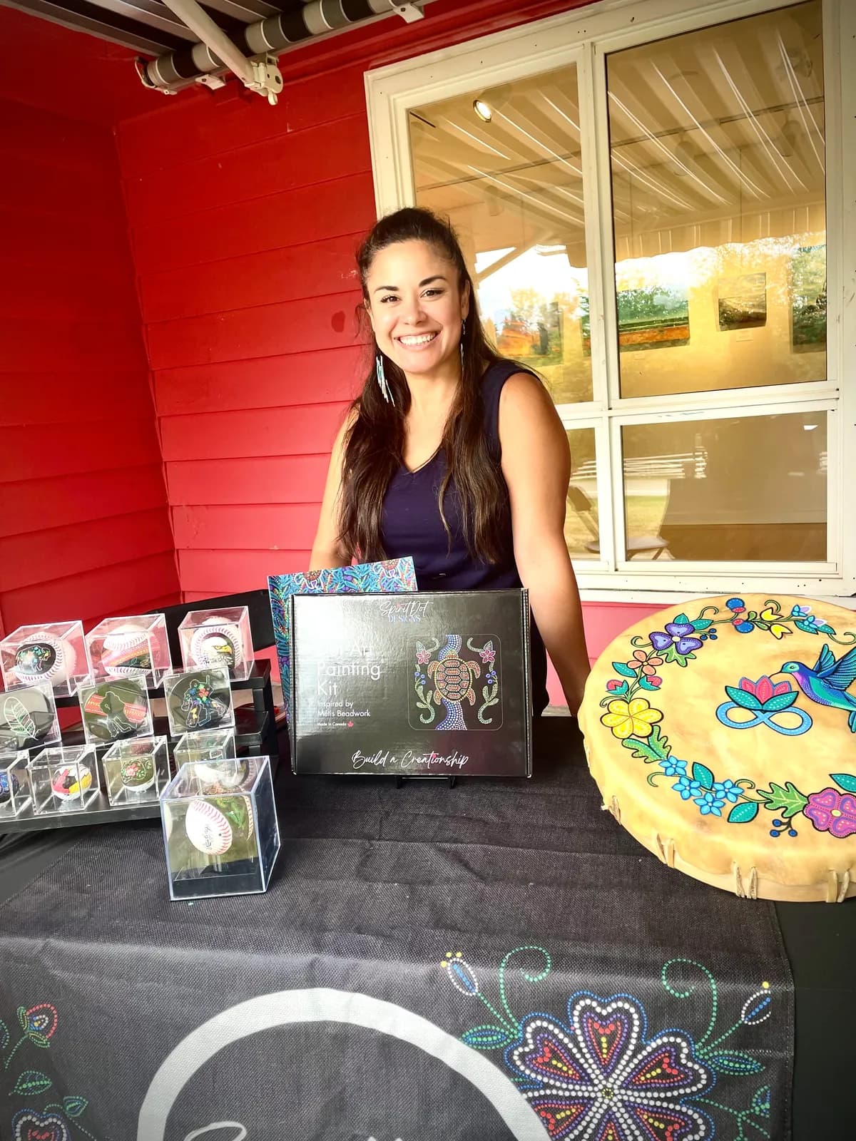 Michelle at her booth with kits and a painted drum